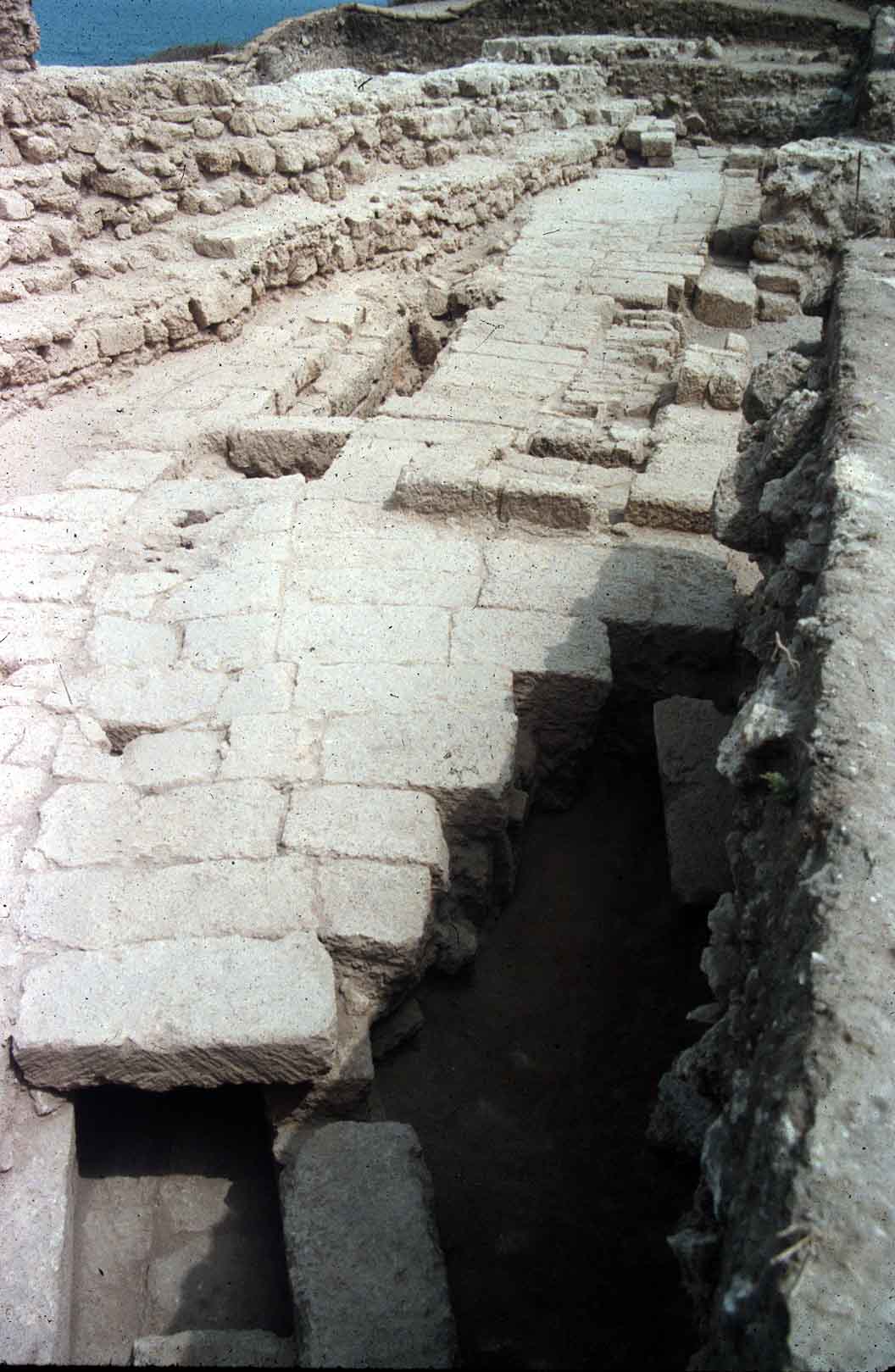The early Roman street and its sewer overlayed by the temple's retaining wall (left)
